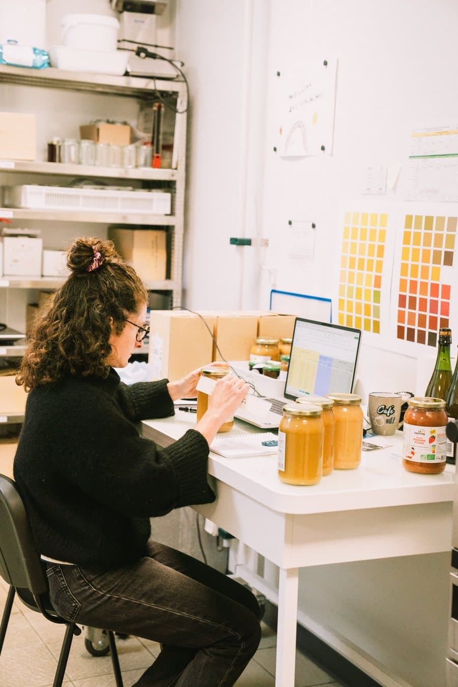 Une collaboratrice du laboratoire consigne ses résultats sur ordinateur, entourée de pots de compote et de nuanciers de couleurs