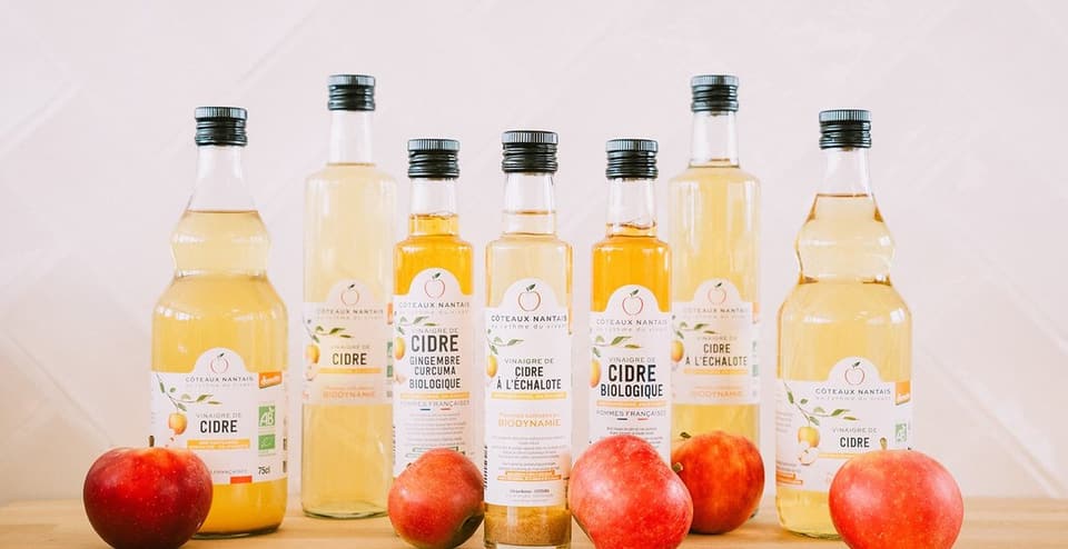 Bottles of organic cider vinegar in front of red apples